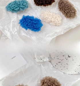 Detail view of colorful plush lamb wool hair clips on a soft decorative background