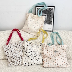 Detail of four colorful printed canvas tote bags with cute animal patterns in home setting