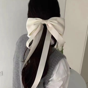 Rear view of a large white velvet ribbon bow hair clip styled on a low ponytail hair
