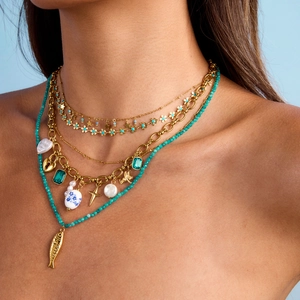 Layered gold necklace with pearls, turquoise beads, and stars on a blue background