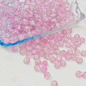 Detailed view of pink crackle glass beads in a blue dish for DIY jewelry making