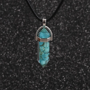 Detailed macro view of a hexagonal turquoise bullet pendant on a black cord necklace