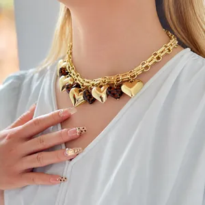 Primo piano di una collana a catena dorata stile hip-hop con ciondoli a cuore su una modella.