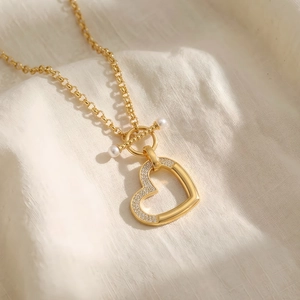 Détail du pendentif cœur doré avec cristaux et fermoir en T avec perles sur tissu