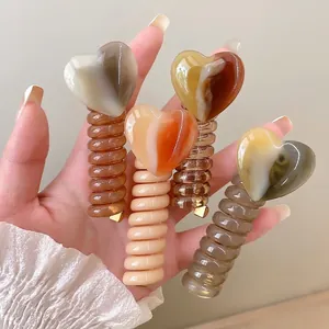 Handheld set of four retro marble heart spiral hair ties in warm earthy tones