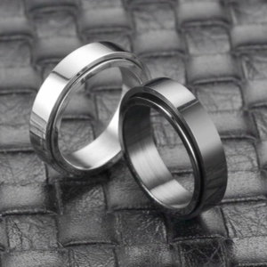 Detail of silver and black spinning titanium rings on a black leather textured background