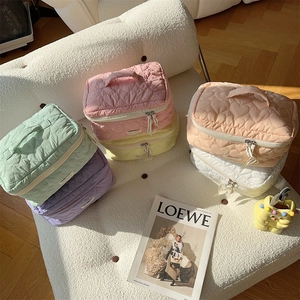 Beauty case trapuntati a cuore in sei colori pastello su un divano bianco morbido
