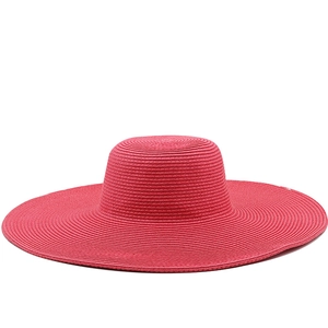 Close-up of rose red woven straw hat with wide brim and flat top for summer sun protection