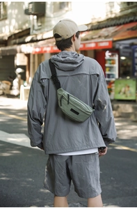 Detail of green fabric chest bag with black adjustable buckle on person in urban street