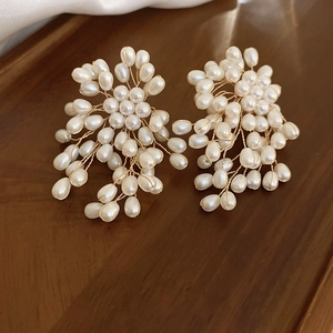 Macro shot of handmade white pearl firework earrings with gold wire weaving