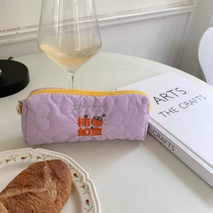 Close-up of lilac quilted stationery pouch with floral embroidery and yellow zipper detail