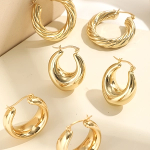 Detailansicht von drei Paaren goldener geometrischer Creolen und dicker Tropfenohrringe
