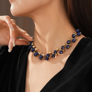Detail view of a vintage necklace with blue lapis beads and gold floral accents on a model