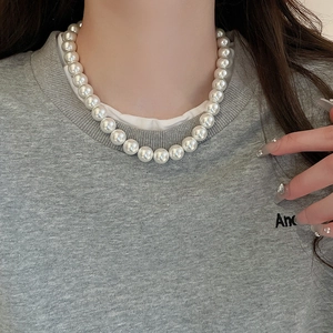 Close-up of white round pearl necklace worn by a model in a minimalist style