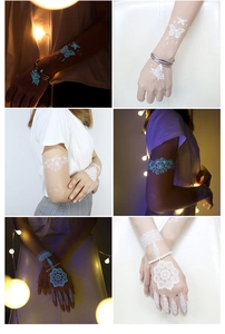 Luminous temporary tattoos showing white butterfly and mandala patterns glowing blue in the dark
