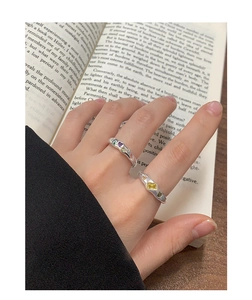 Detail of S925 silver rings with colorful zircon insets on an open book background
