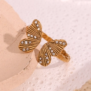 Detailed view of 18K gold butterfly ring with white zircons on a textured stone base