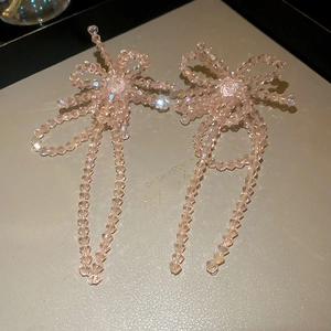Détail de boucles d'oreilles nœuds en perles de cristal rose avec longues franges