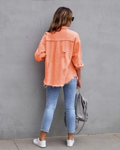 Rückansicht der orangefarbenen Jeansjacke mit schweren Destroyed-Effekten und Saumfransen