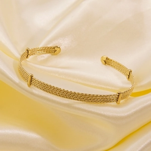 Macro shot of 14k gold plated titanium steel open cuff with five-strand woven texture