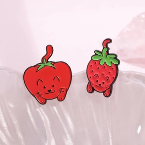Cute enamel cat brooches in chili and strawberry designs on decorative ceramic plate