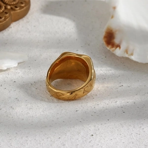 Retro style 18k gold plated ring with irregular lava texture on white sand background