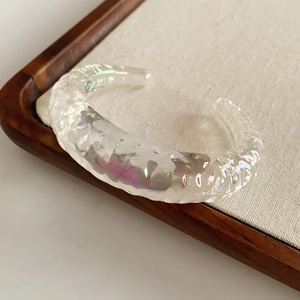Close-up of irregular iridescent acrylic cuff bracelet with colorful water ripple textures