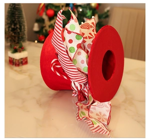 Detail view of a red velvet Christmas tree top hat with striped bows on a marble surface
