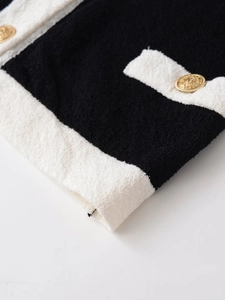 Close-up of black and white tweed fabric texture with decorative gold embossed button