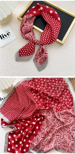 Detailed view of red silk scarf with white polka dots and paisley patterns in a knot