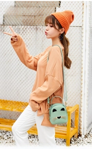 Close-up of mint green cat-shaped mini shoulder bag with 3D ears on a female model