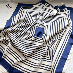 Detailed view of the smooth silk-like satin fabric and navy blue geometric stripe pattern