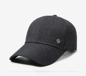 Detail of gray twill baseball cap with square metal emblem and stiff curved brim