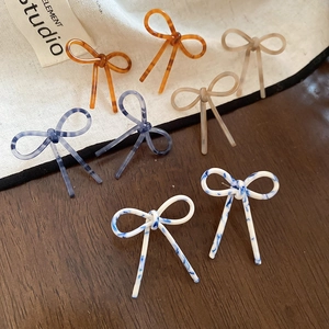 Gros plan détaillé de quatre couleurs de boucles d'oreilles nœuds en acétate sur un tissu