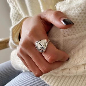 Close-up of vintage wide oval 925 silver ring worn on index finger against knit fabric