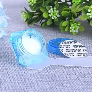 Blue translucent cosmetic jar with white cream, safety seal, and applicator scoop