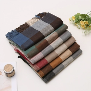 Close-up of stacked colorful plaid scarves with soft fringes and cozy cashmere-like texture