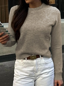 Dettaglio di un maglione in maglia beige a maniche lunghe con scollo rotondo su una modella