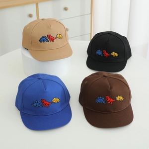 Détail des motifs de dinosaures brodés sur des casquettes de baseball pour enfants