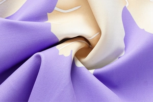 Dettaglio macro del tessuto con stampa floreale astratta con volant viola e crema