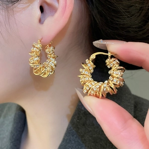 Détail macro de boucles d'oreilles créoles dorées torsadées avec micro-pavé de zircon
