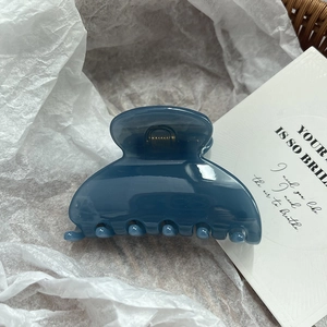 Primo piano di una molletta per capelli blu scuro lucido su sfondo estetico bianco