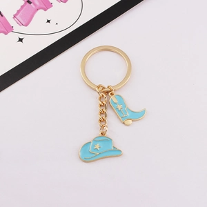 Detail view of blue cowboy hat and boot charms on a gold alloy metal keychain