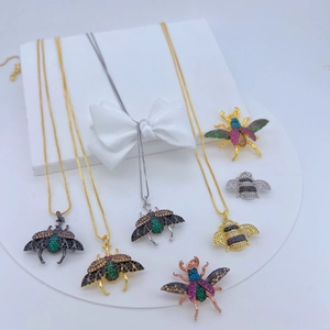 Collection of insect-shaped pendants and brooches with colorful zircons on white displays
