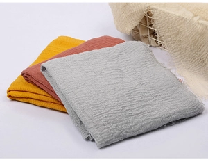 Detail of multi-layered muslin fabric with crinkle texture and fringed edges in three colors