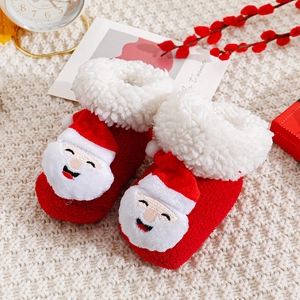 Detail der roten Weihnachts-Babysocken mit 3D-Weihnachtsmann auf weißem Strickteppich