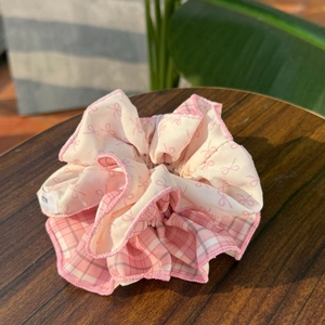 Pink plaid scrunchie with bow patterns on a wooden table with home decor background