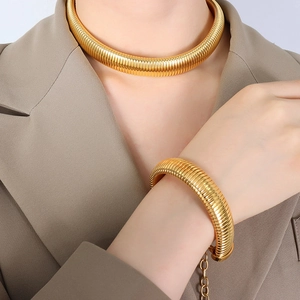Chunky 18K gold plated titanium necklace and bracelet set worn by a fashion model