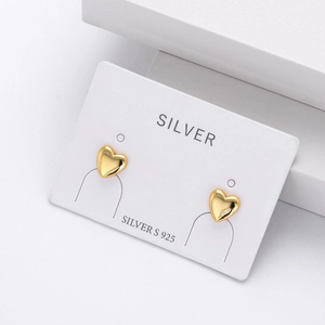 Close-up of polished gold heart stud earrings on a white card made of 925 silver