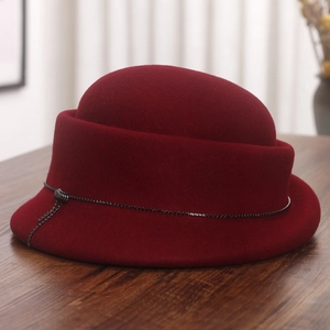Detail of burgundy wool cloche hat featuring elegant black bead chain trim on wooden surface